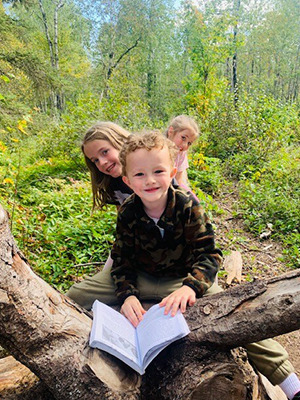 Three happy students outside in the forest with a booklet