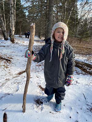 Child holding walking stick in snow