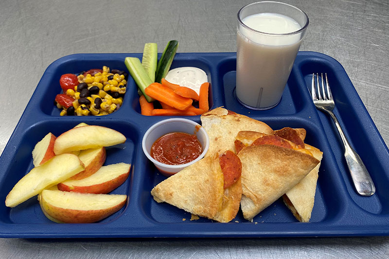 Calzones with marinara sauce, apple slices, cucumber and carrot with ranch, bean and corn salsa, and milk