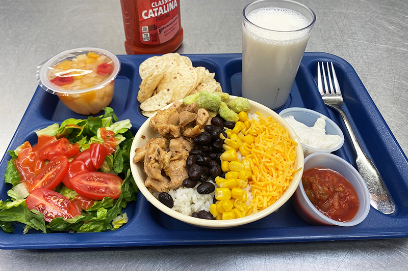 Chicken burrito bowl, tortilla chips, fruit, and milk