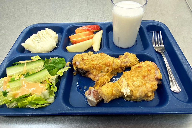 Chicken drumsticks, mashed potatoes, green salad, fruit, and milk