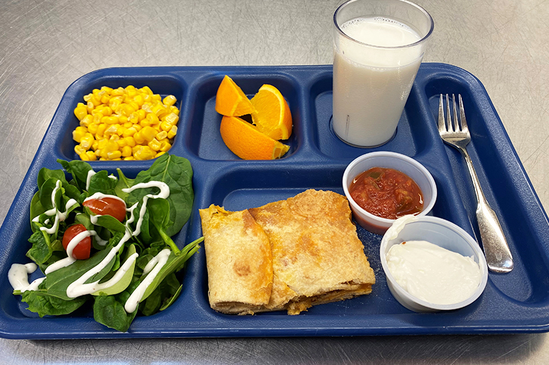 Quesadilla, salad, corn, orange slices, and glass of milk