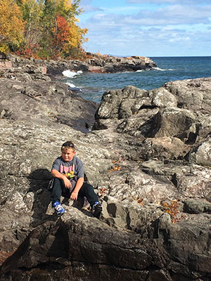Boy sitting on the rocks by the lake