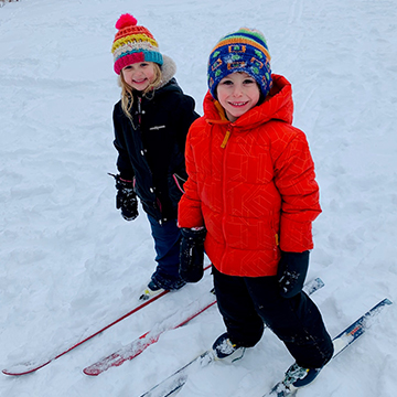 Two happy students skiing in the snow